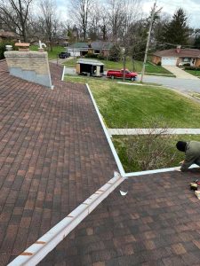 View from atop a residential roof with a worker providing a gutter repair
